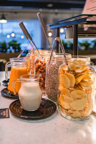 Lähikuva lounasannoksesta, jossa Ståhlbergin omia lihapullia kermakastikkeessa, krutonkeja, slaattia ja perunamuusia. Taustalla lasi kotikaljaa ja lautanen jolla hampurilainen ja ranskalaisia burgerbuffasta.