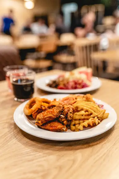 Lähikuva siipibuffet annoksesta. Lautasella ristikkoperunoita ja wingsejä