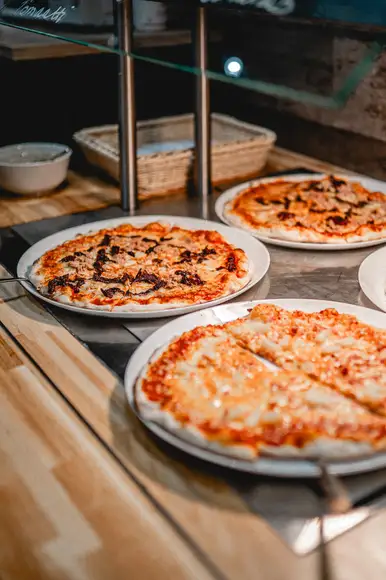 Lähikuvassa 3 erilasita pizzaa pizzabuffassa.