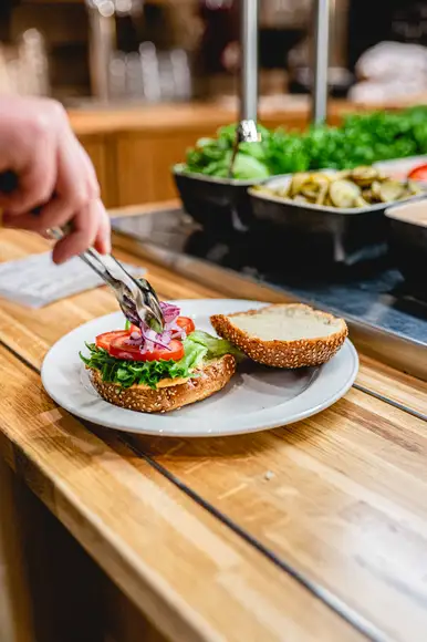 Kuvassa asiakkaan käsi joka on rakentamassa omaa hampurilaista burgergbuffasta.