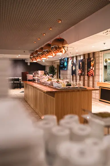 Lähikuva lounasannoksesta, jossa Ståhlbergin omia lihapullia kermakastikkeessa, krutonkeja, slaattia ja perunamuusia. Taustalla lasi kotikaljaa ja lautanen jolla hampurilainen ja ranskalaisia burgerbuffasta.